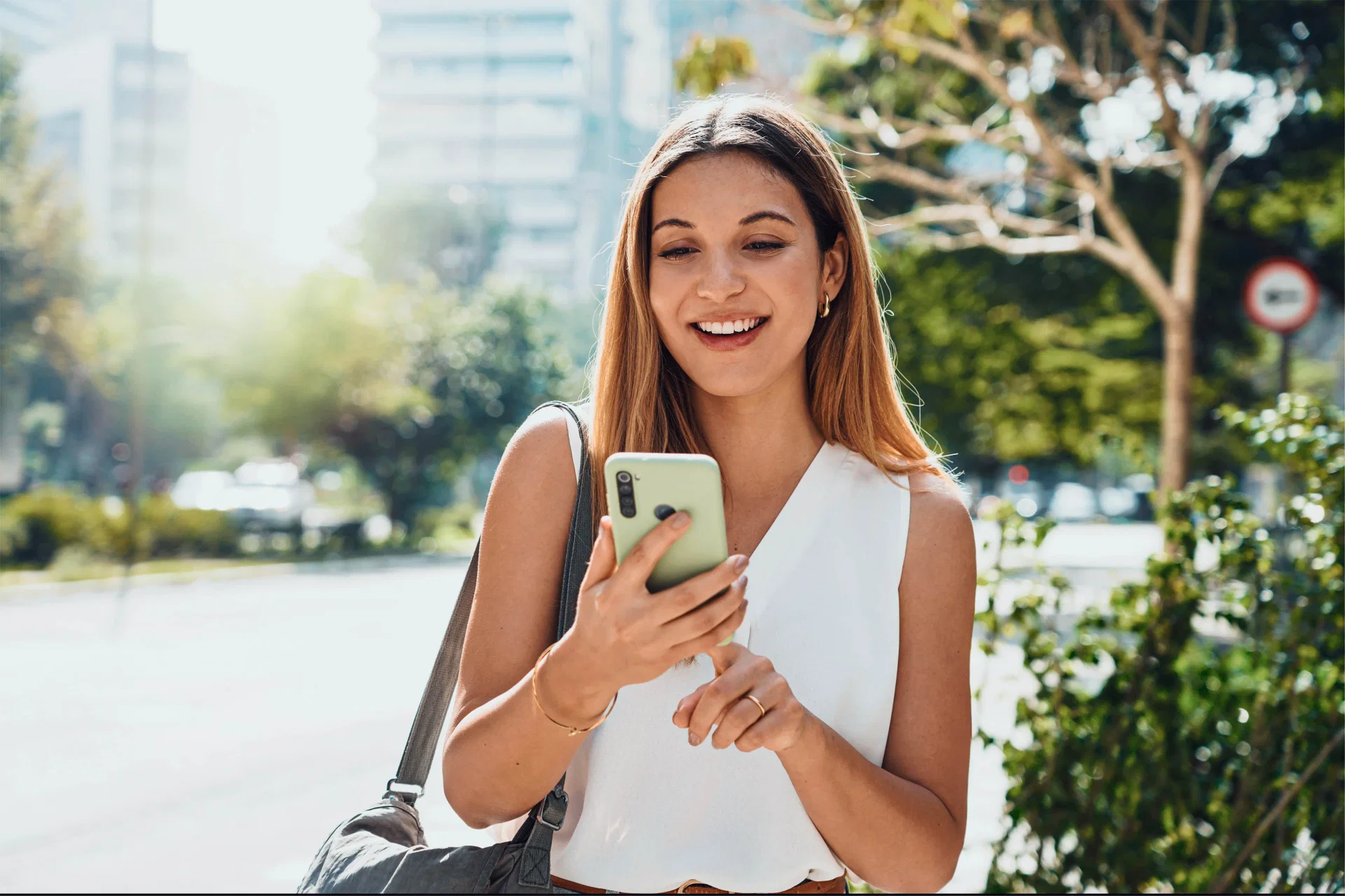 Pix Agendado - foto de uma mulher em ambiente externo mexendo no celular e sorrindo